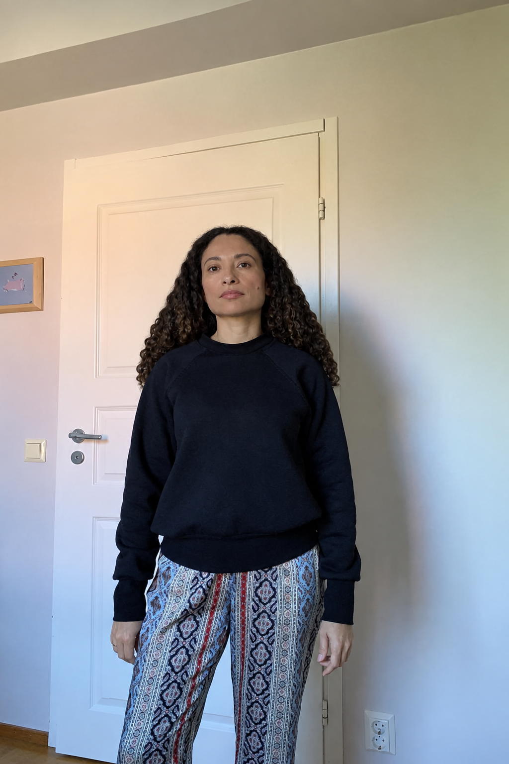 Modelo com camisola preta e calças estampadas, com frizz do cabelo suavizado